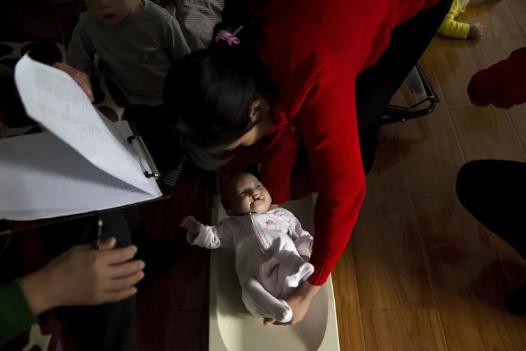Person holding baby with cleft lip next to another person holding a clipboard
