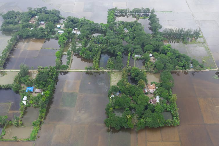 Farm fields under water and some houses stranded around flood waters