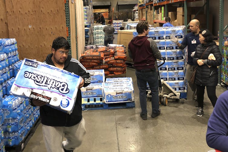 Shoppers rush to pick up toilet paper that had just arrived at a Costco store on March 7, 2020, in Tacoma, Wash.