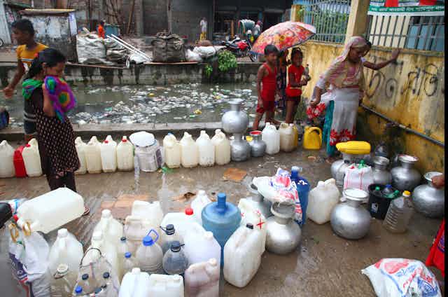Bangladeshi people collecting drinking water from a water pump inside a stree
