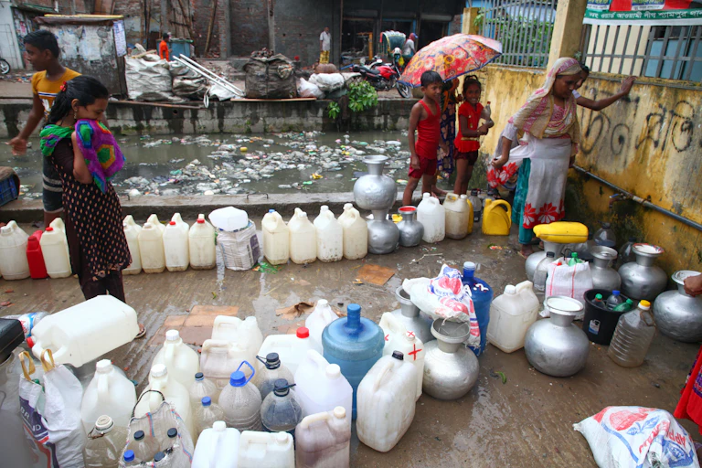 Bangladeshi people collecting drinking water from a water pump inside a stree