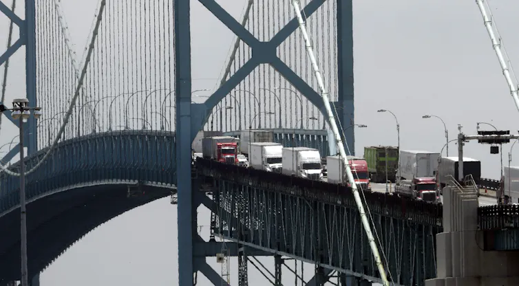 Une grande rangée de camions de transport traverse un pont.