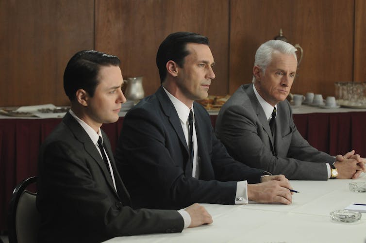a photo from the show Mad Men; 3 white men in business suits sitting at a table.