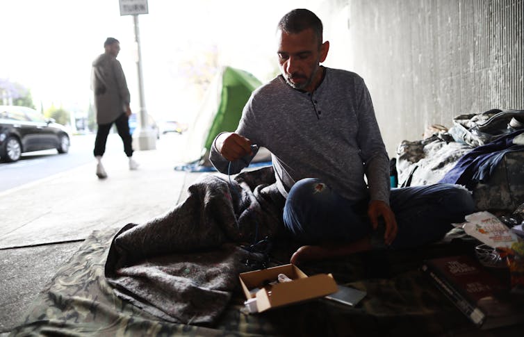 A homeless Navy veteran in Los Angeles, on a sidewalk with a blanket and some possessions.