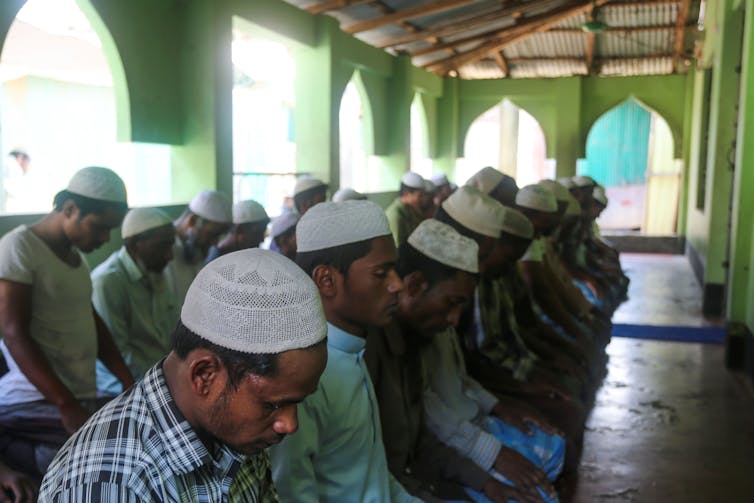 men bowing at prayer in mosque, photo by Getting images, open link to view all details