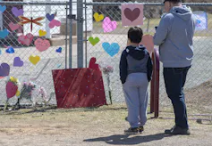 a man and a boy in front of a makeshift memorial