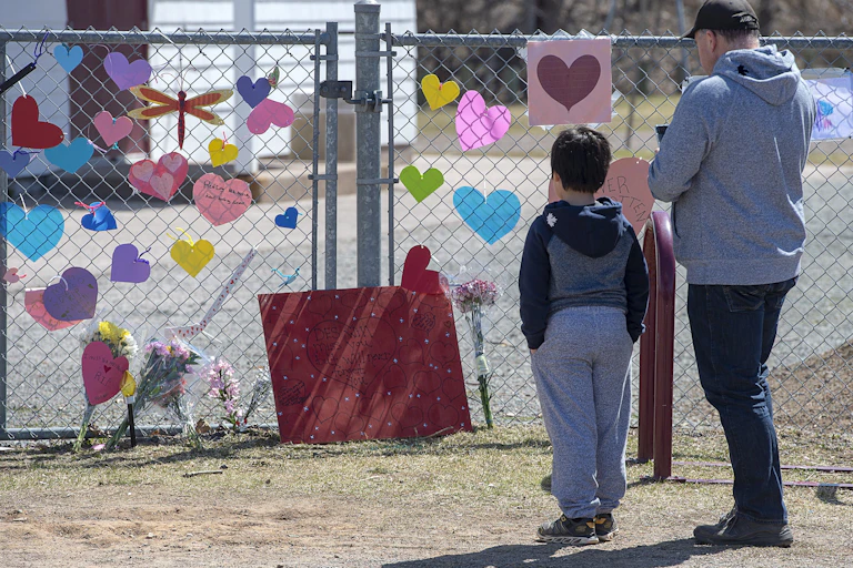 a man and a boy in front of a makeshift memorial