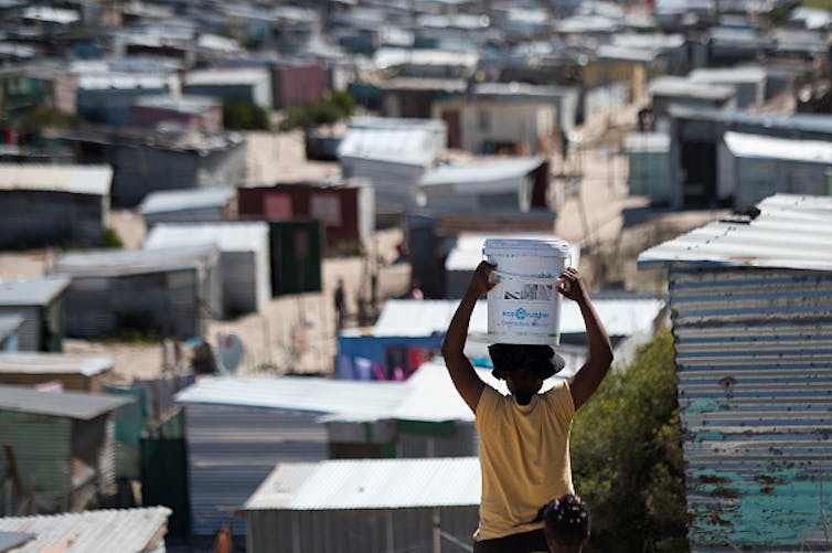 A woman carries a bucket of fresh water to an informal settlement in Khayelitsha, near Cape Town. South Africa has the widest wealth gap in the world. Photo by RODGER BOSCH/AFP via Getty Images A woman carries a bucket of fresh water to an informal settlement in Khayelitsha, near Cape Town. South Africa has the widest wealth gap in the world. Photo by RODGER BOSCH/AFP via Getty Images