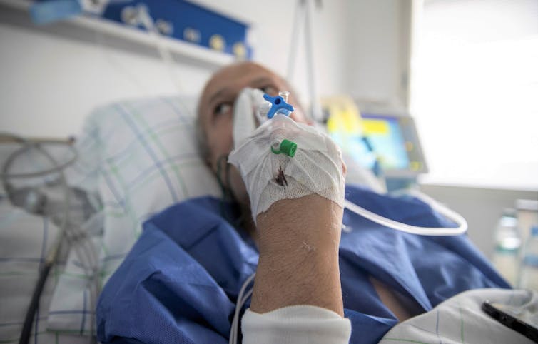 chaplain holds a tablet for a patient to communicate with his family