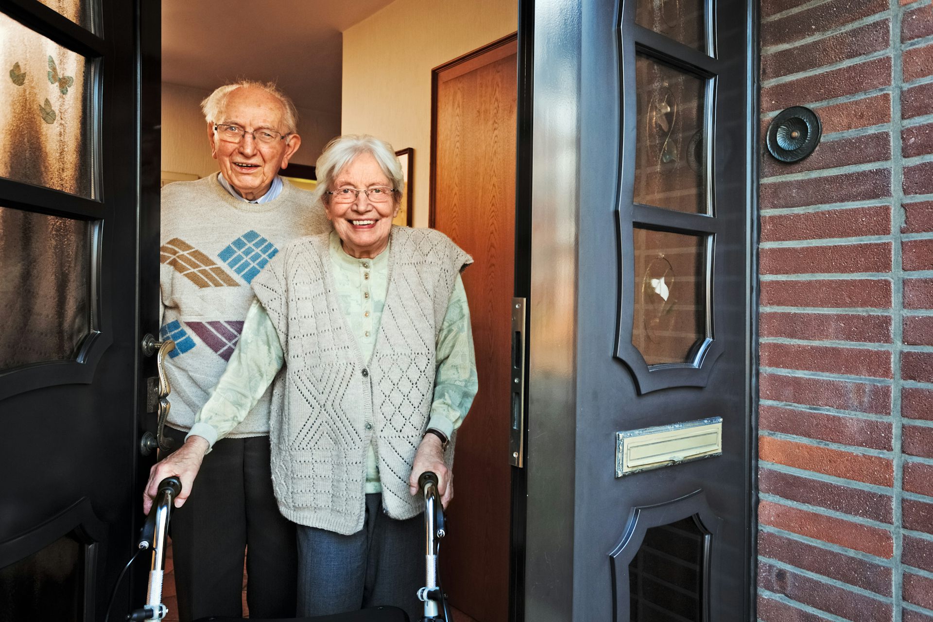 Happy elderly couple opening front door