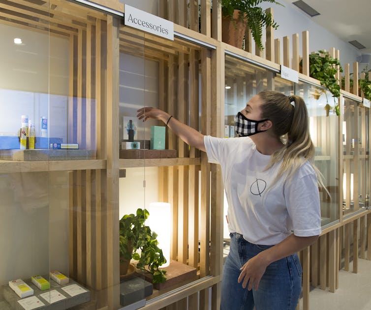 A woman reaches into a display cabinet at a cannabis store