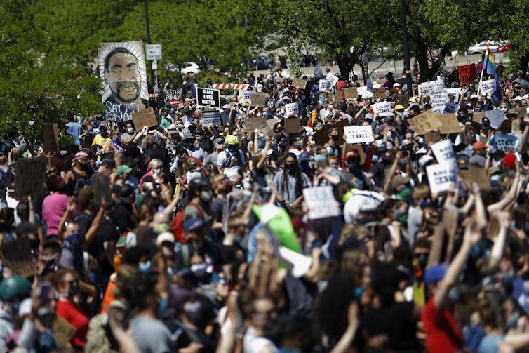 Hundreds of protesters holding signs and images of George Floyd.