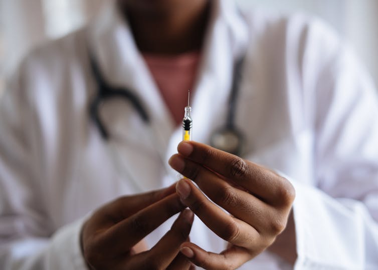 Health-care worker prepares a syringe for injection.