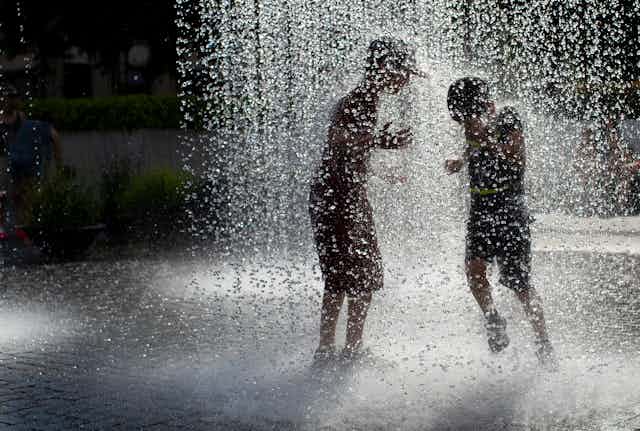Two boys cool off in a fountain
