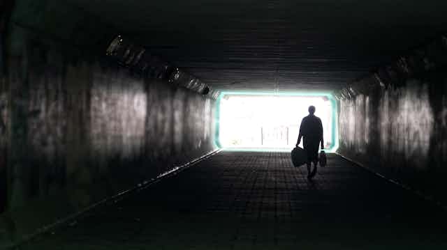 Person walking alone in dark city tunnel