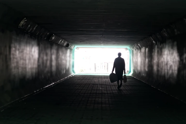 Person walking alone in dark city tunnel