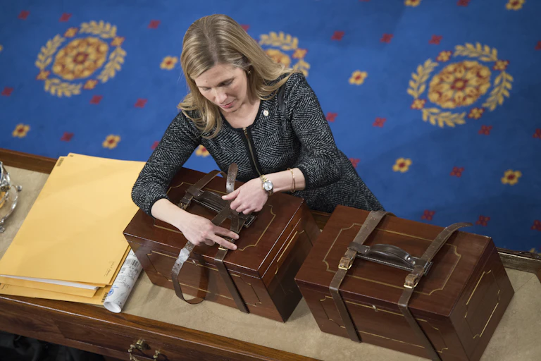 A woman unbuckles a strap around a box.