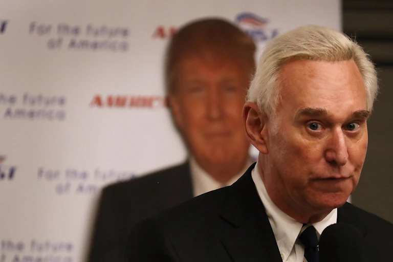 Roger Stone in front of a poster showing an image of Donald Trump.