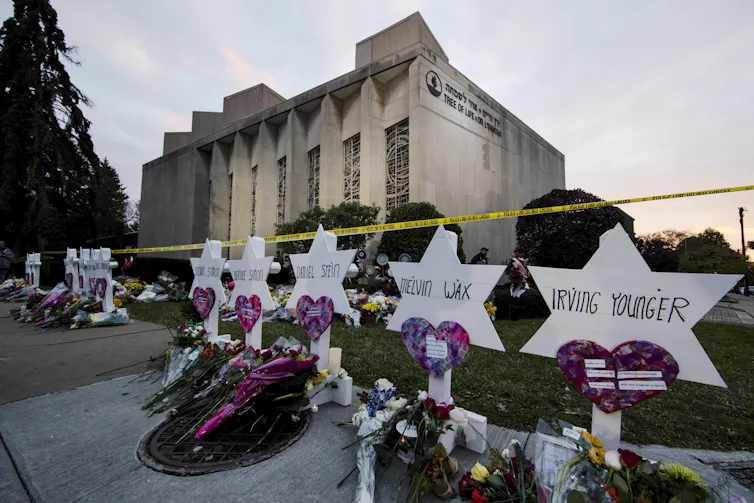 Flowers lie at the base of markers with the names of those who died