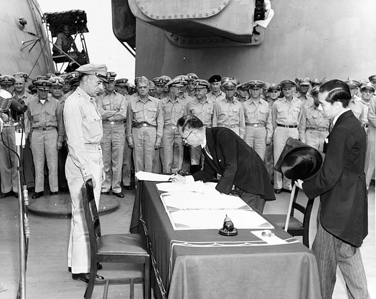 Japanese foreign affairs minister Mamoru Shigemitsu signs the Japanese Instrument of Surrender aboard the USS Missouri as General Richard K. Sutherland watches