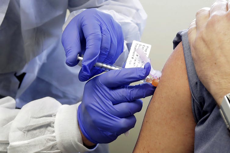 A person is injected with a potential vaccine during a clinical trial.