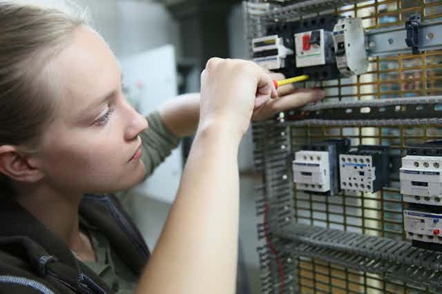 Young woman learning to set up electrical circuit.