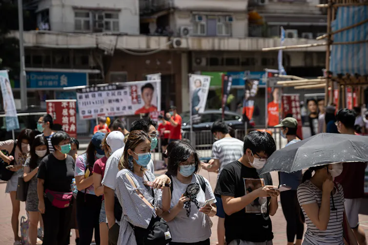 A queue of people on a Hong Kong street wearing face masks.