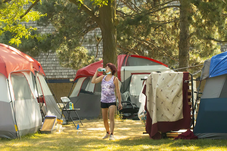 A woman sips a bottle of water amid tents at a homeless encampment in Toronto.