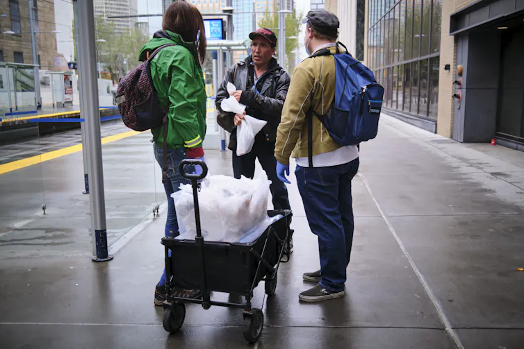 Volunteers chat with a homeless man on a street in Calgary.