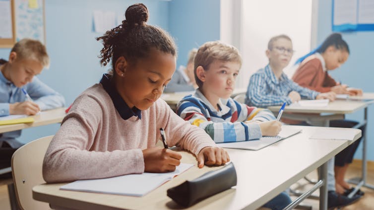 A classroom of students who are middle-school aged are writing a test.