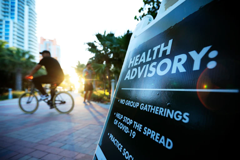 A sign in Miami reflects how cities have resorted to issuing their own protective rules as coronavirus case numbers climb.