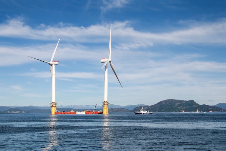 Two floating wind turbines with a ship in between.