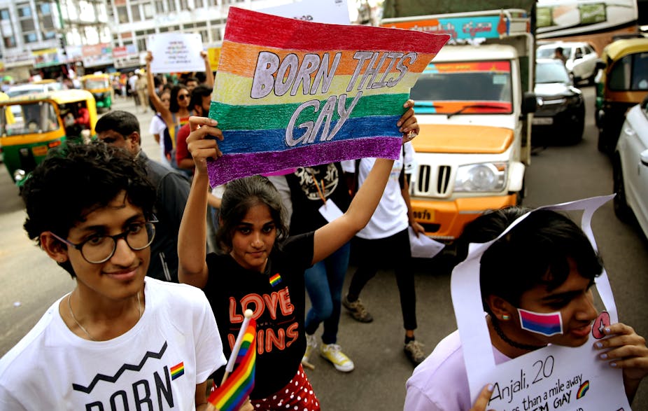 Woman in India holding sign that says born is gay