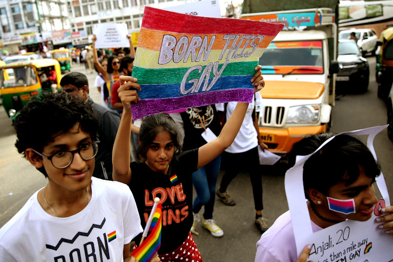 Woman in India holding sign that says born is gay