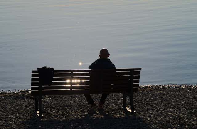 Image of a man sitting alone on a bench. 