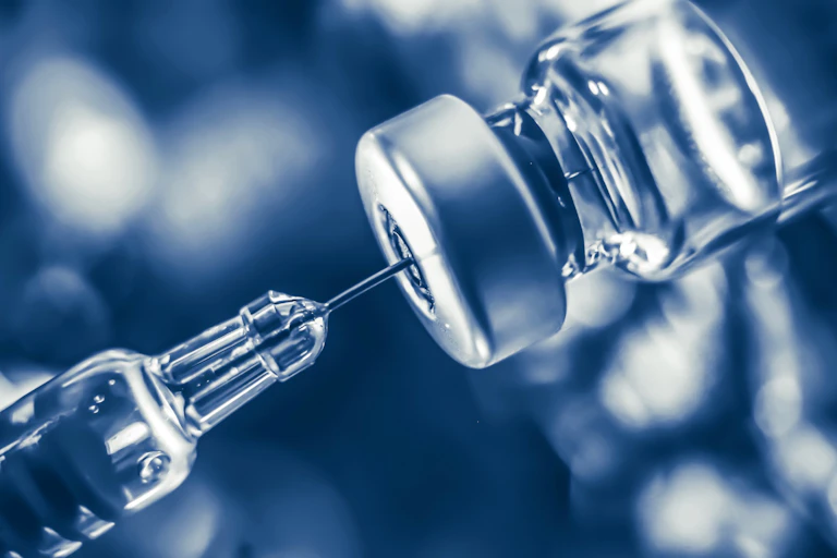 A syringe being filled with vaccine fluid