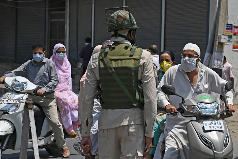 Soldier speaks with people wearing face masks
