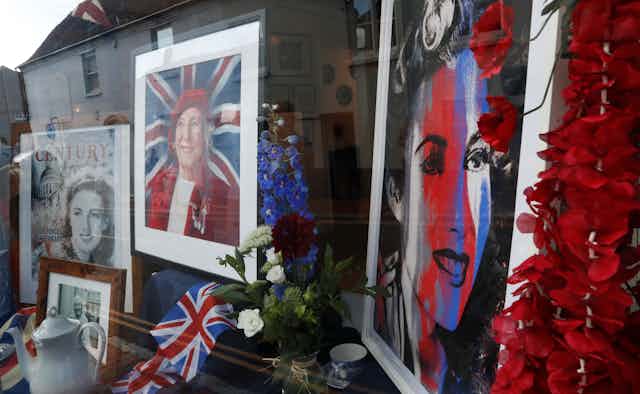 Photos of Vera Lynn as a young and older woman are seen in a window, with the Union Jack flag, a teapot and flowers,  as her funeral procession goes through the village of Ditchling, southern England, July 10, 2020. 