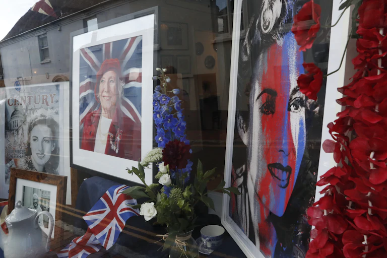 Photos of Vera Lynn as a young and older woman are seen in a window, with the Union Jack flag, a teapot and flowers, as her funeral procession goes through the village of Ditchling, southern England, July 10, 2020.