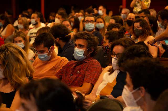 Seated crowd of people wearing masks