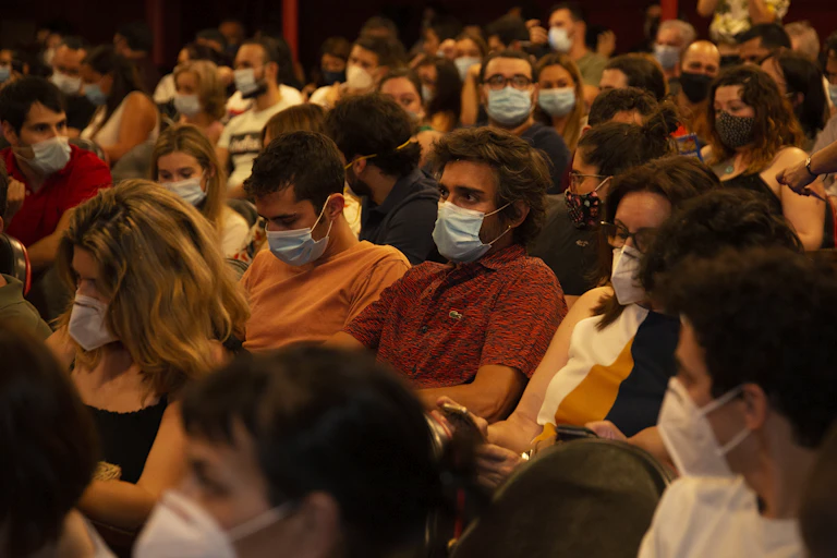 Seated crowd of people wearing masks