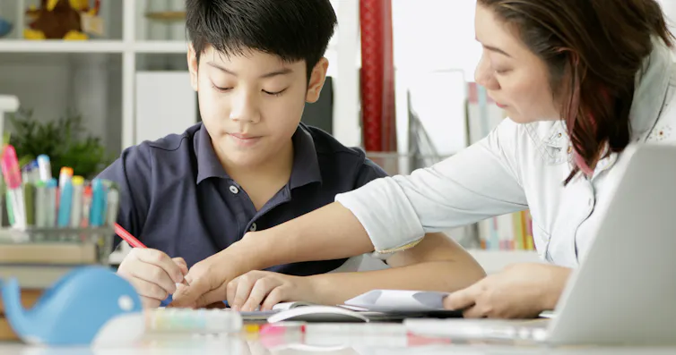 A mother is helping her teenage son do homework