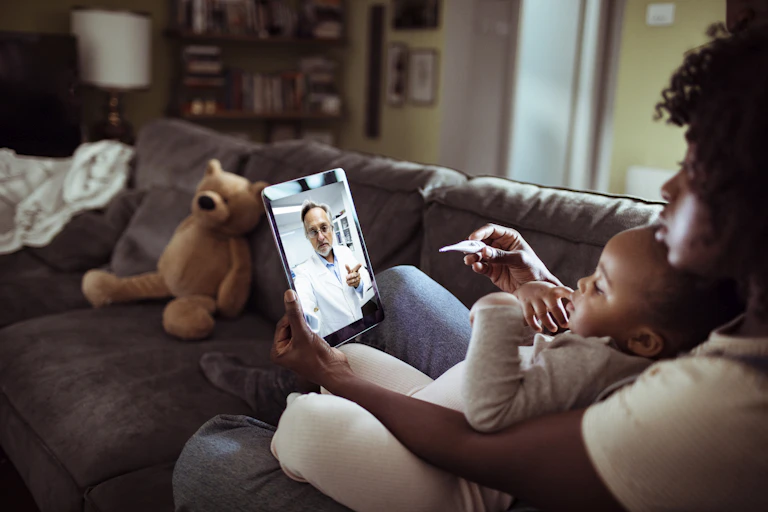 Woman with baby talking to doctor through a video chat.