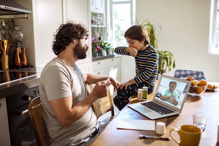 A father and son on a video call with a doctor.