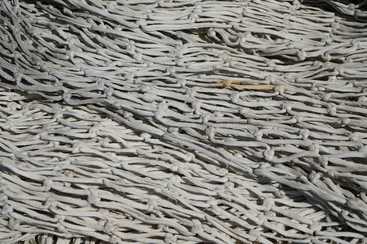 An empty industrial fishing net, grey and white in colour.
