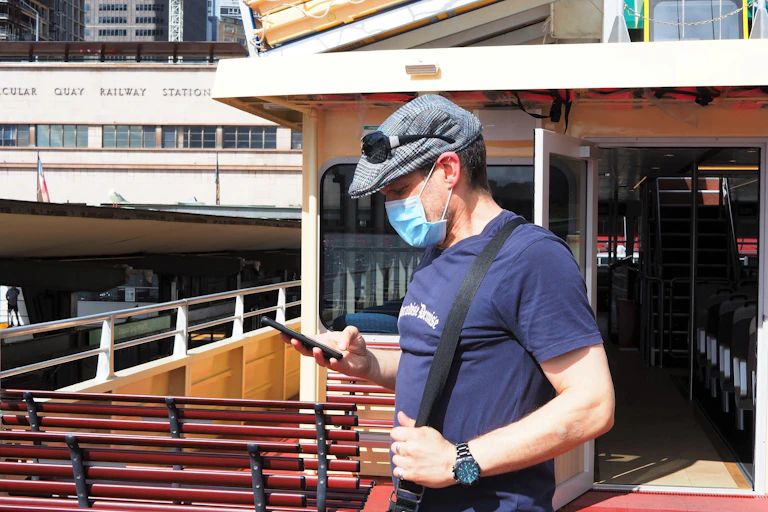 Man wearing mask stares at mobile phone.