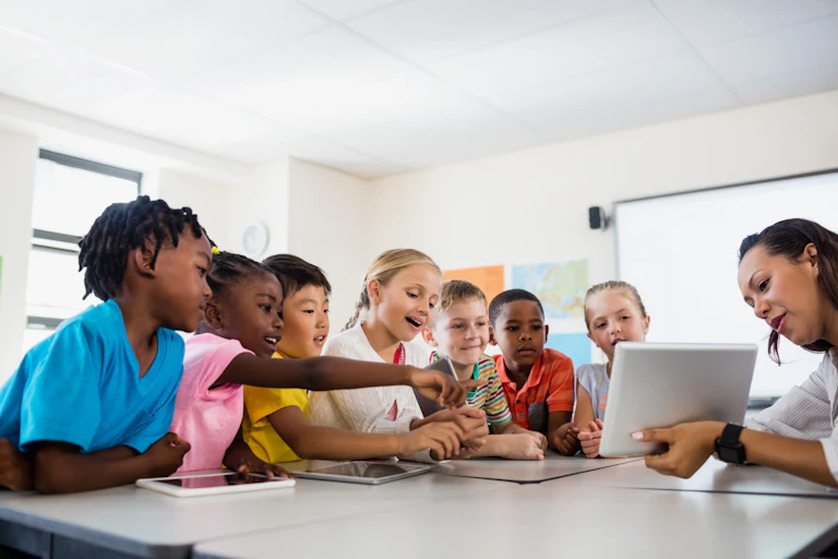 children looking at digital tablet held by teacher