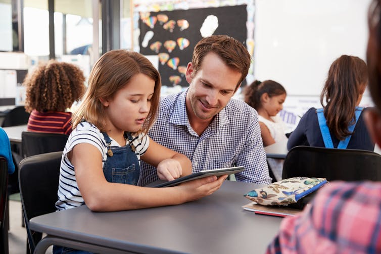 Teacher and girl looking at computer tablet.