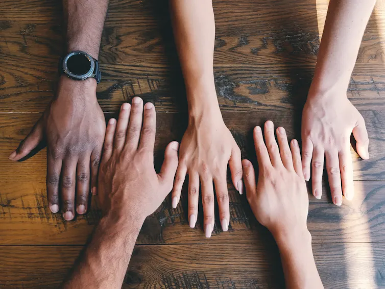 Five hands on a table