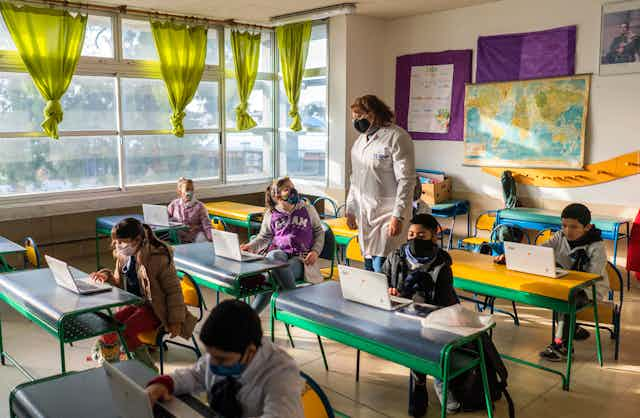 Students and a teacher wearing face masks in a classroom 